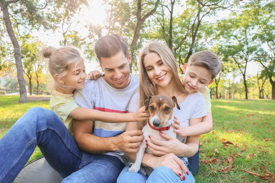Famille avec deux enfants et un chien, assis dans l'herbe d'un parc